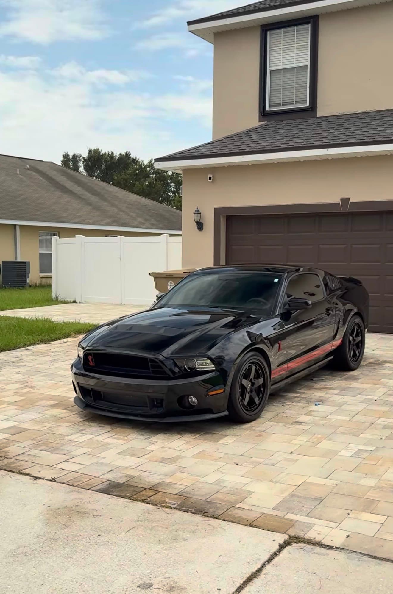 Black Ford Mustang Shelby detailed with a glossy finish in front of a garage