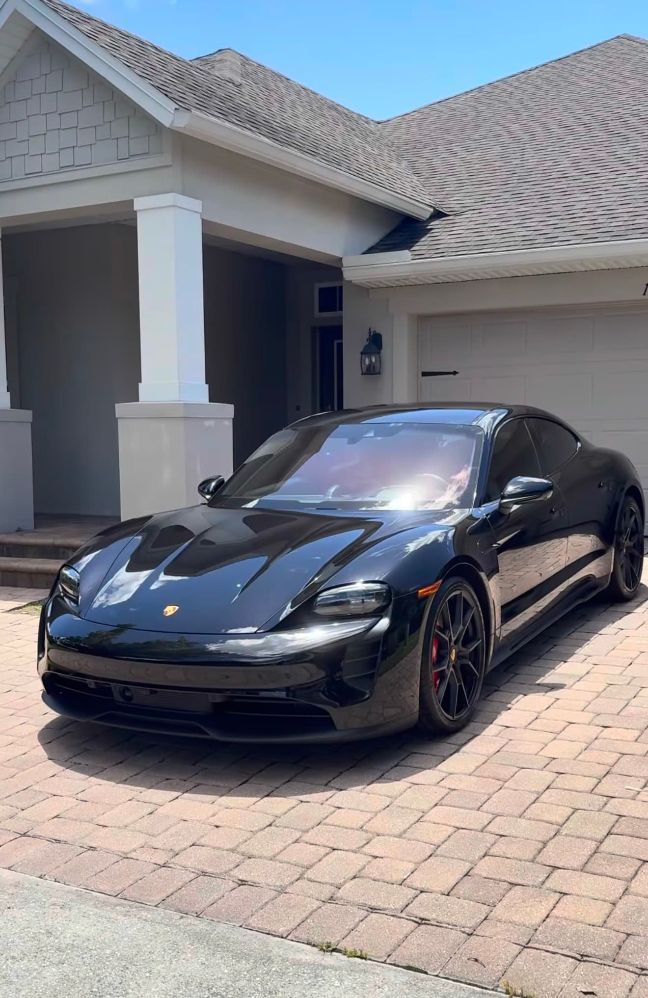 Black Porsche Taycan detailed to a deep gloss in a residential driveway